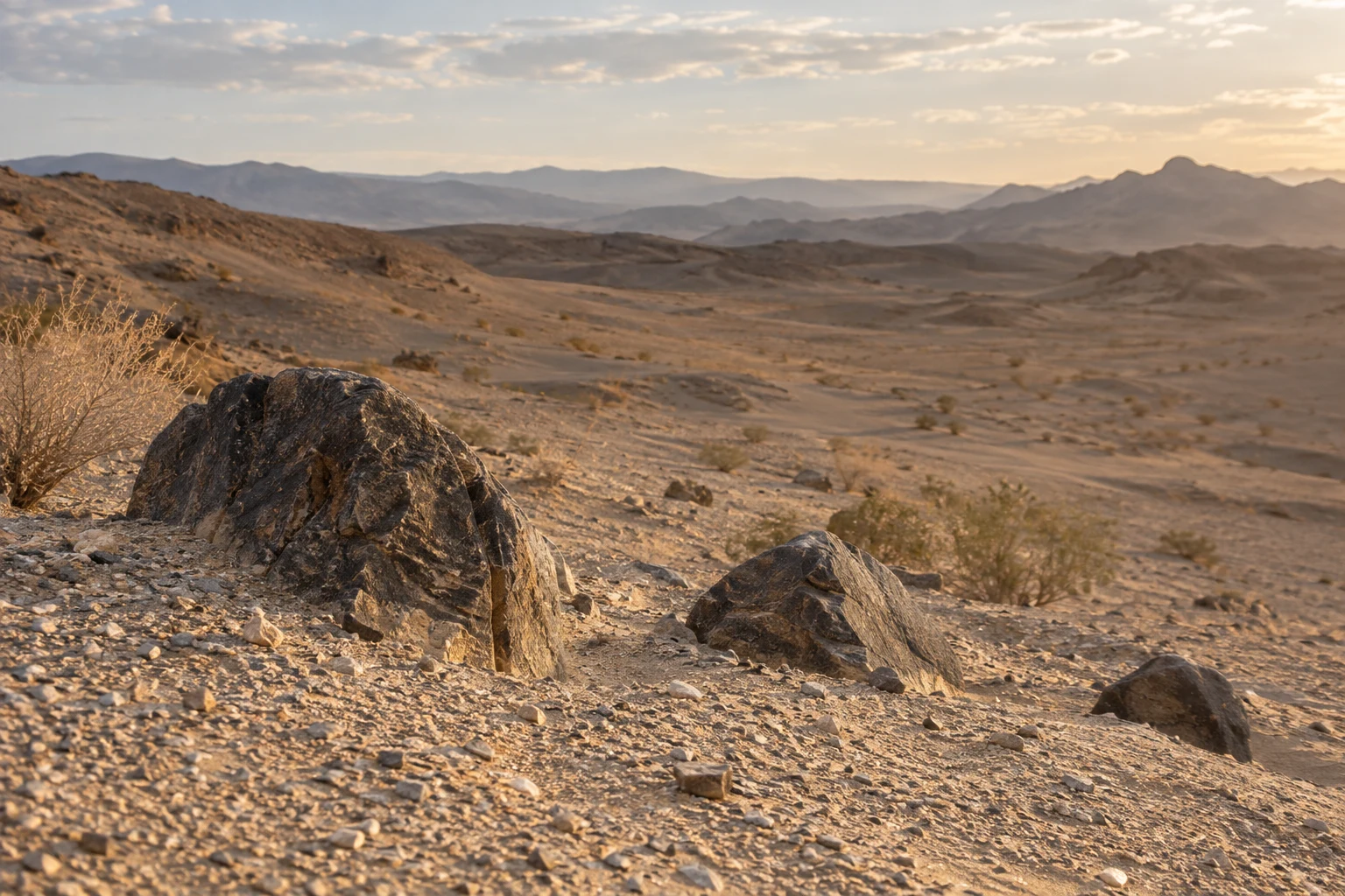 Three differently sized dark stones partly buried in pale desert gravel.