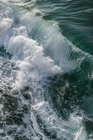 Dense whitewater spills diagonally across a deep-green wave, breaking into fine foam.