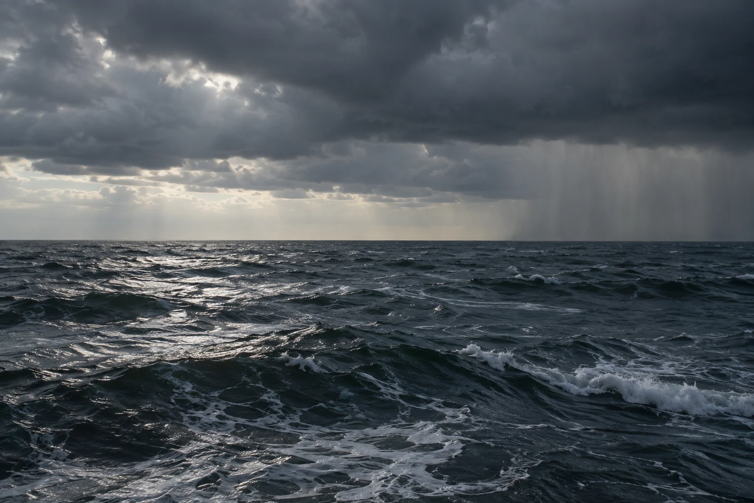 Dark rolling water lies beneath a low storm cloud and a distant curtain of rain.