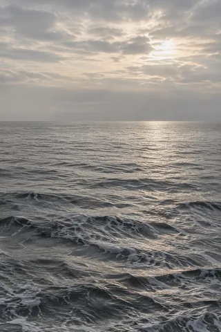 Pearly light breaks through clouds and traces a silver path across small dark waves.