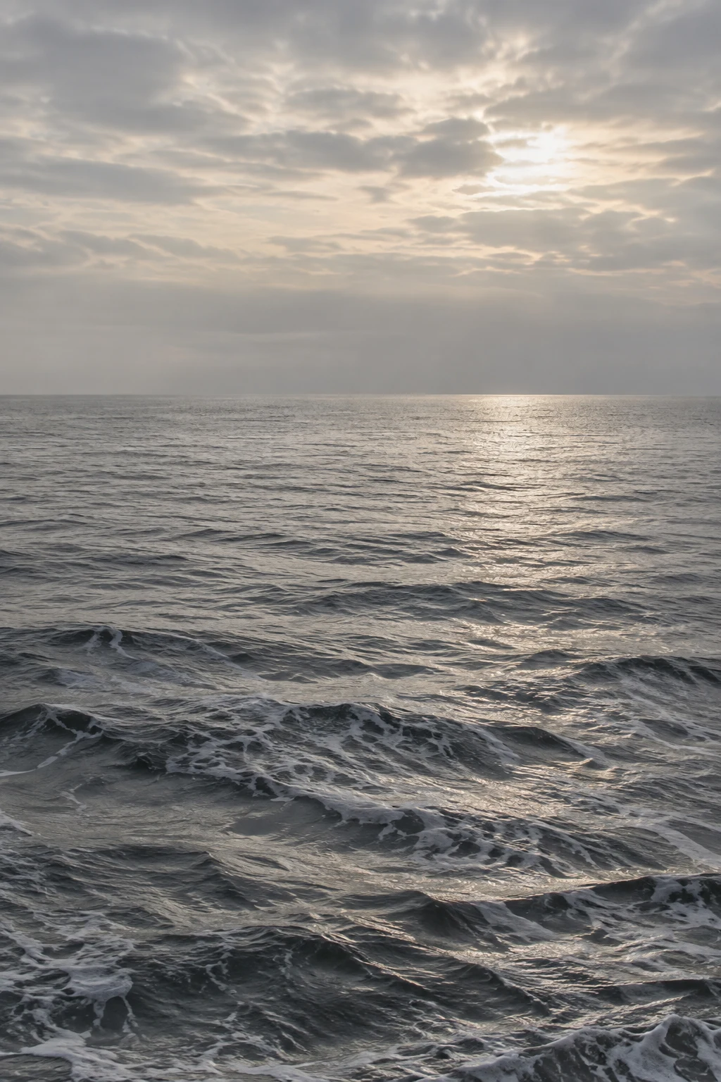 Pearly light breaks through clouds and traces a silver path across small dark waves.