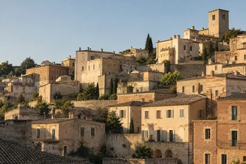 Terraced cream and terracotta buildings with shuttered windows, tiled roofs and a plain square tower.