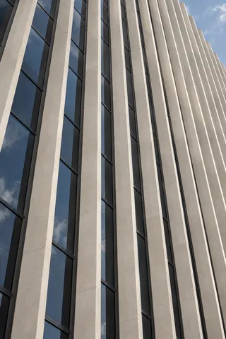 A close upward view of slender pale facade fins separated by blue-gray window strips.