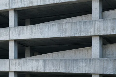 A close exterior view of an empty concrete parking structure with open bays and a diagonal ramp.