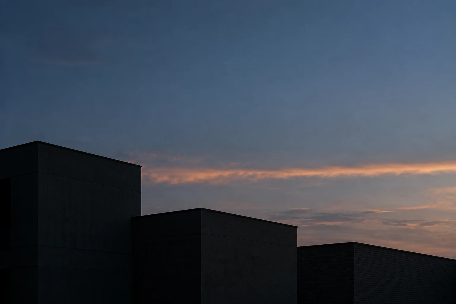 Three anonymous flat-roof buildings in shadow below a blue-gray evening sky and muted peach clouds.